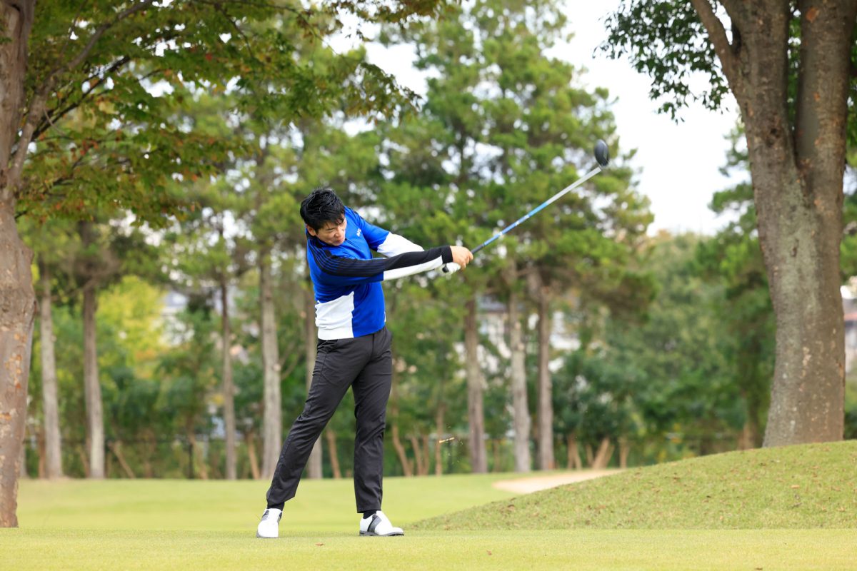ゴルフのショットを打つ吉田洋一郎コーチ