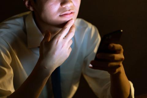 夜中にスマホを操作する男性のイメージ写真