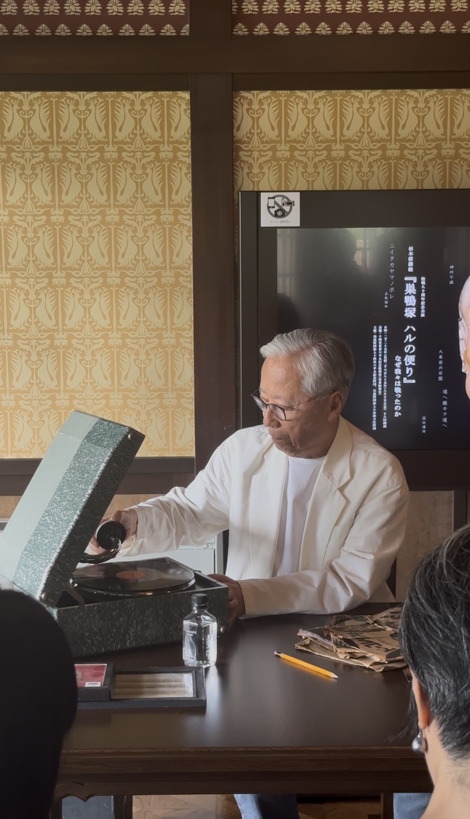 古い蓄音機に太平洋戦争の戦況を告げるNHKラジオニュースの実況録音レコードをかける杉本
