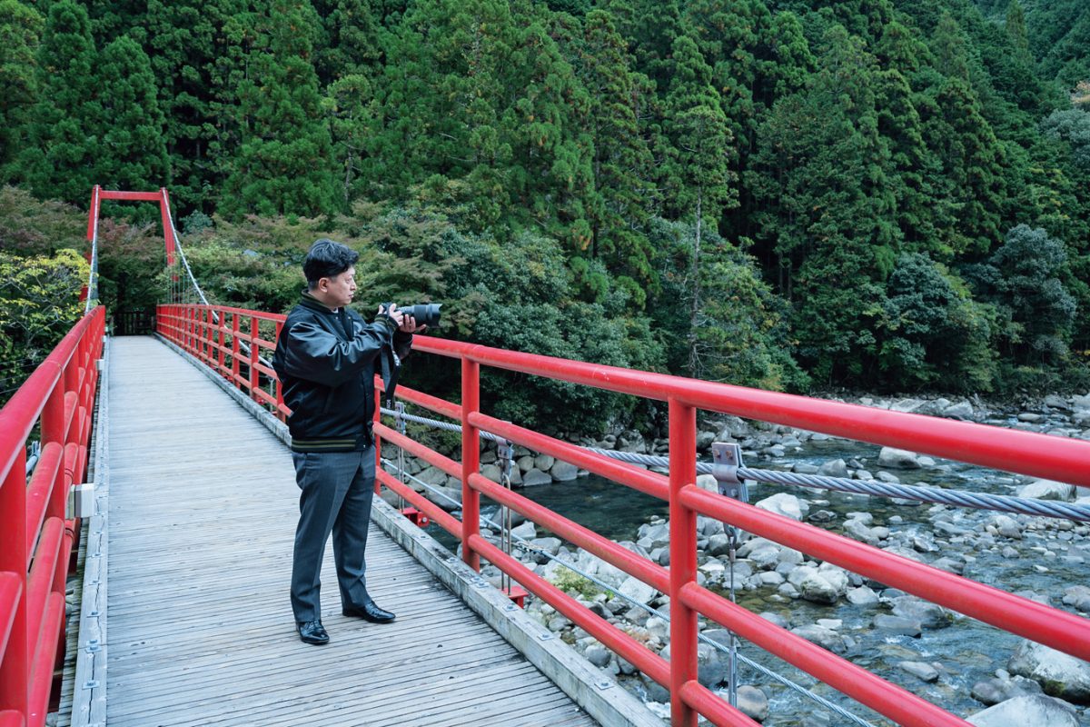 橋の上で撮影する廣松慶久氏